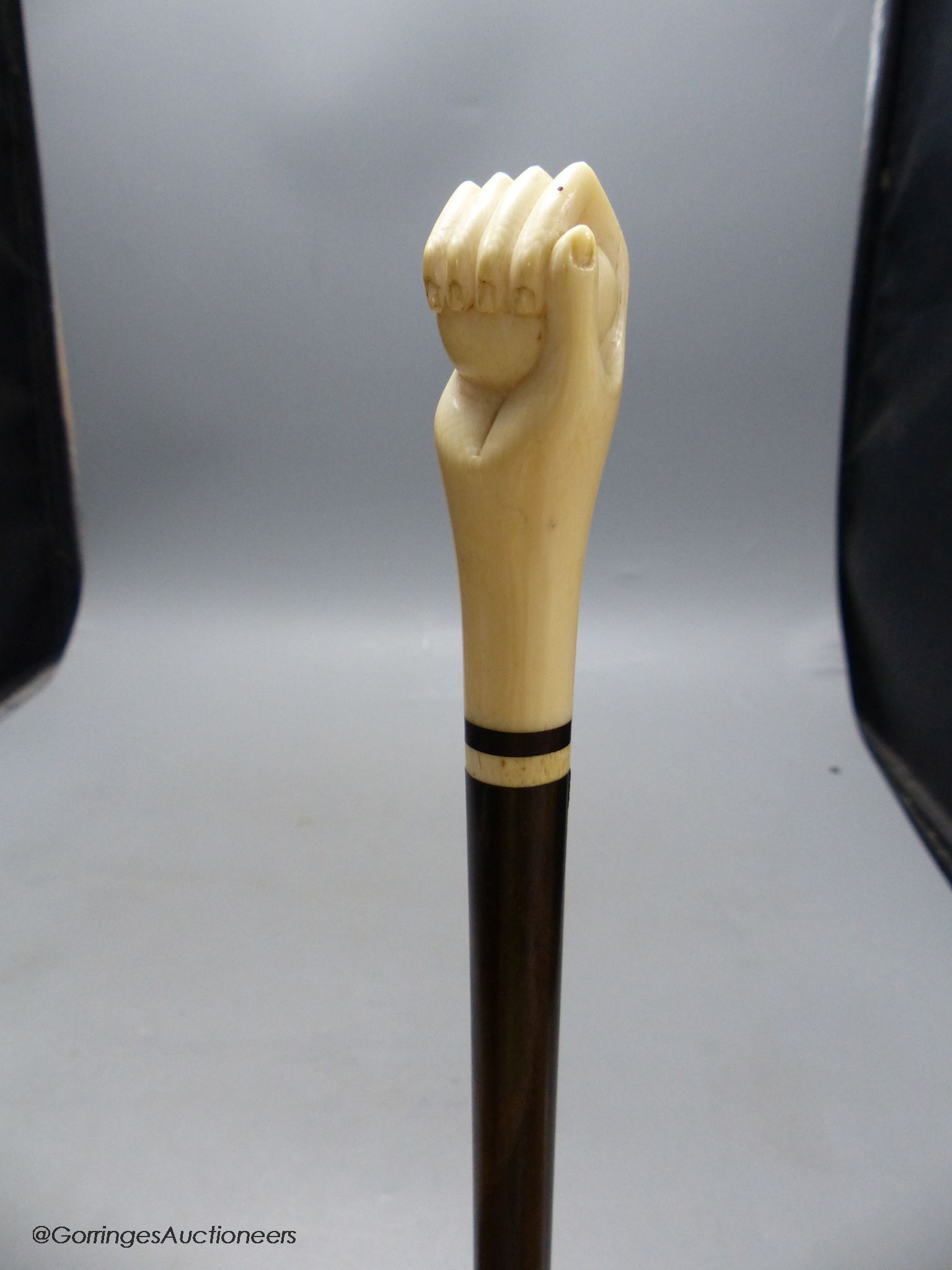 A rosewood and ivory handled walking stick in the form of a hand holding a ball